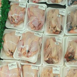 Plastic-wrapped raw chickens neatly arranged on supermarket shelves, ready for purchase.